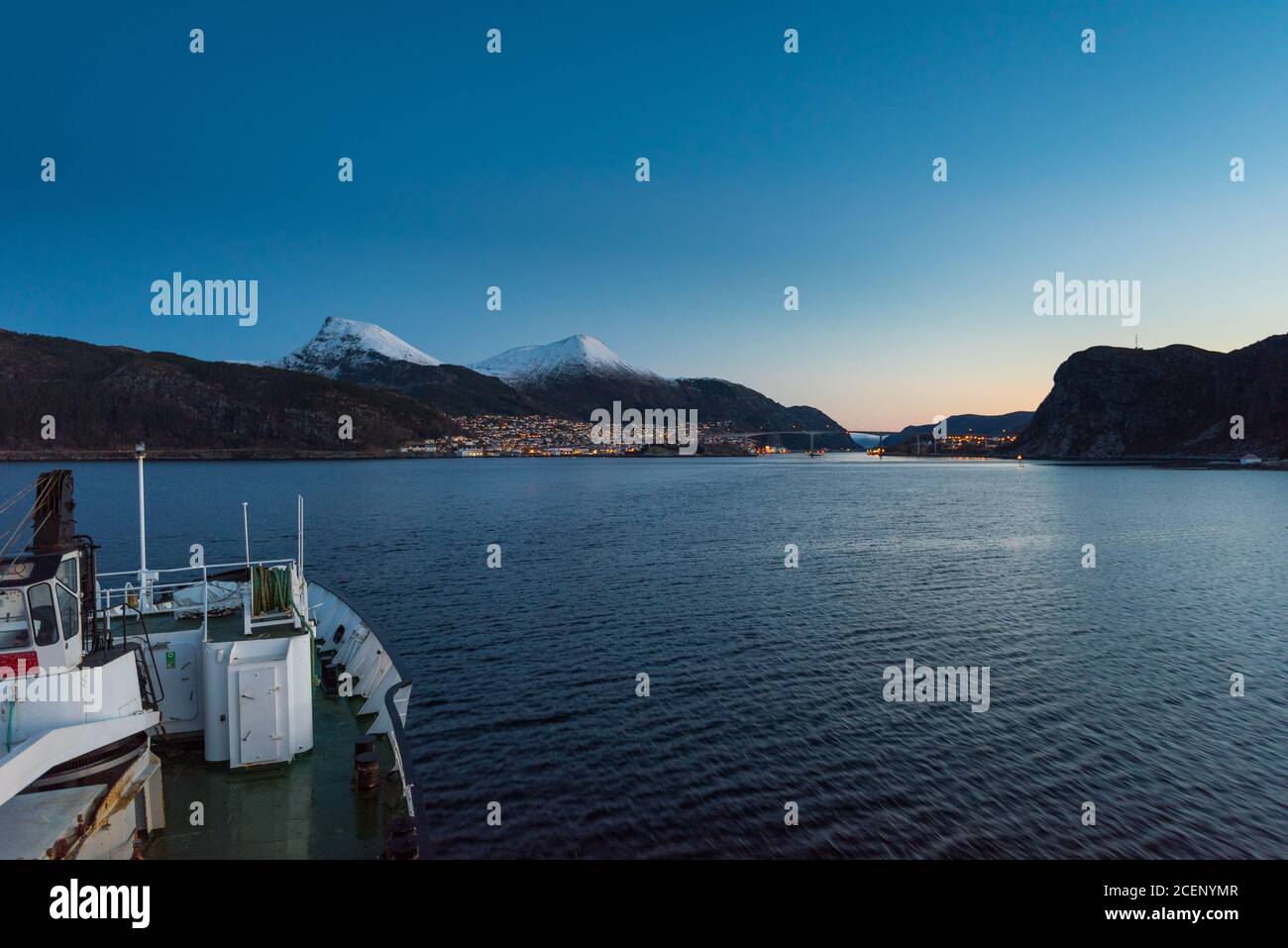 Arriving in Maloy, Norway with cruise ship in early morning with snow capped mountains on clear winter day Stock Photo