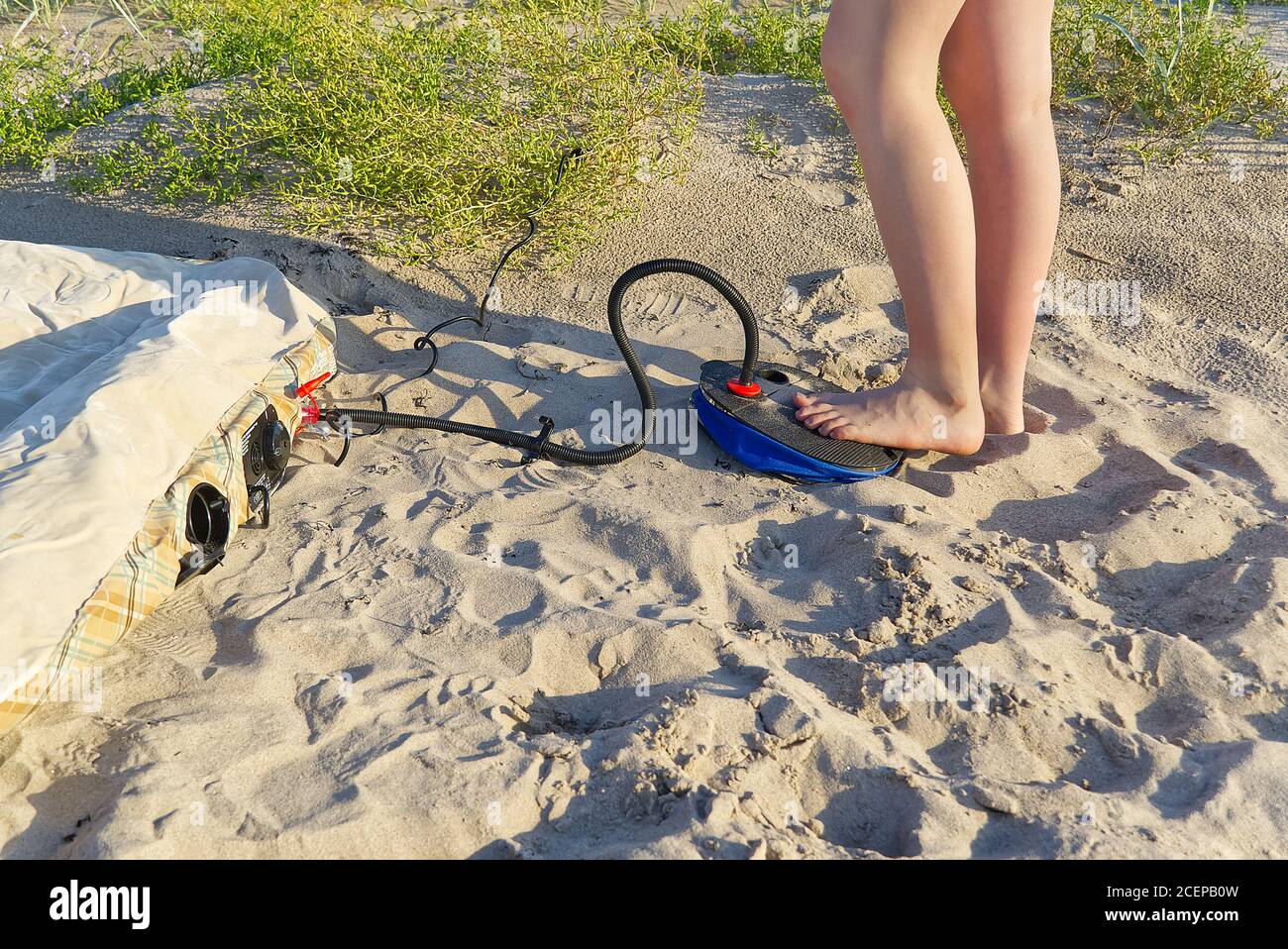 A woman with air foot pump pumps an inflatable mattress or air bed at sandy  beach. Foot inflates air mattress with foot pump on sand Stock Photo - Alamy