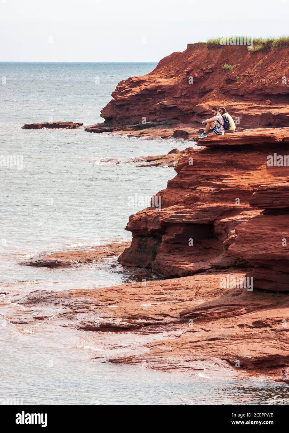 Couple enjoying the scenery from a lookout point. Red sandstone promontory on the Gulf of Saint Lawrence. Oceanview Lookoff, PEI National Park, Canada Stock Photo