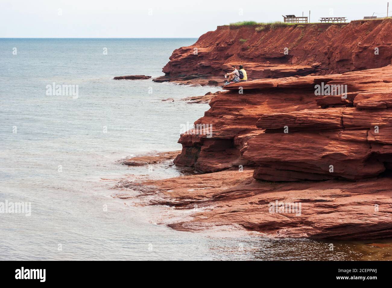 Couple enjoying the scenery from a lookout point. Red sandstone promontory on the Gulf of Saint Lawrence. Oceanview Lookoff, PEI National Park, Canada Stock Photo