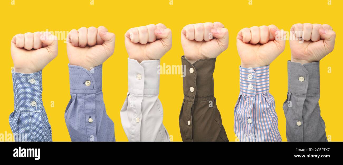 Male hands in fists in different shirts on yellow background. Protest and indignation. Hand gesture signals Stock Photo