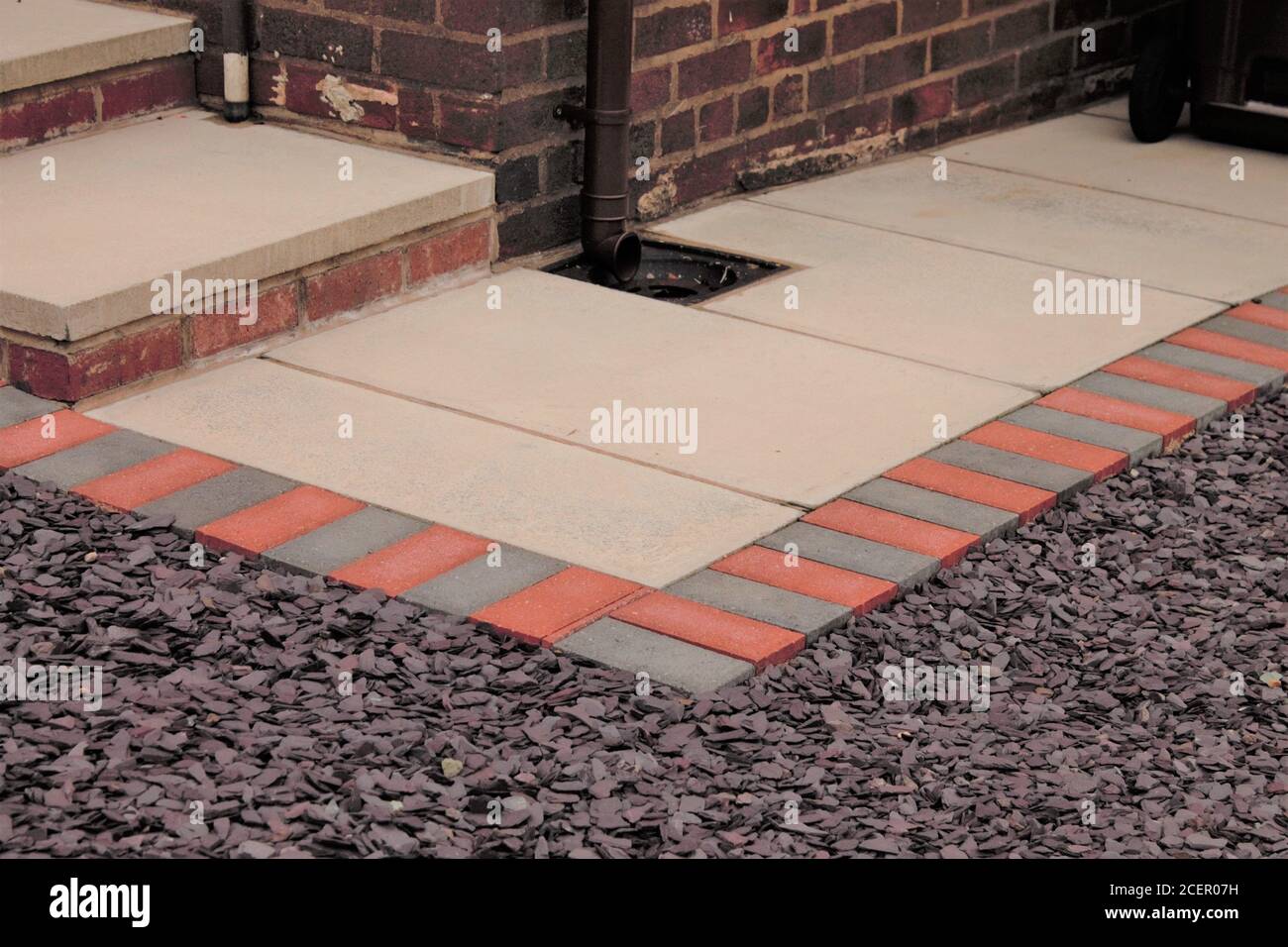 low maintenance garden paving, white paving slabs with grey and red block edging surround by slate shingles Stock Photo
