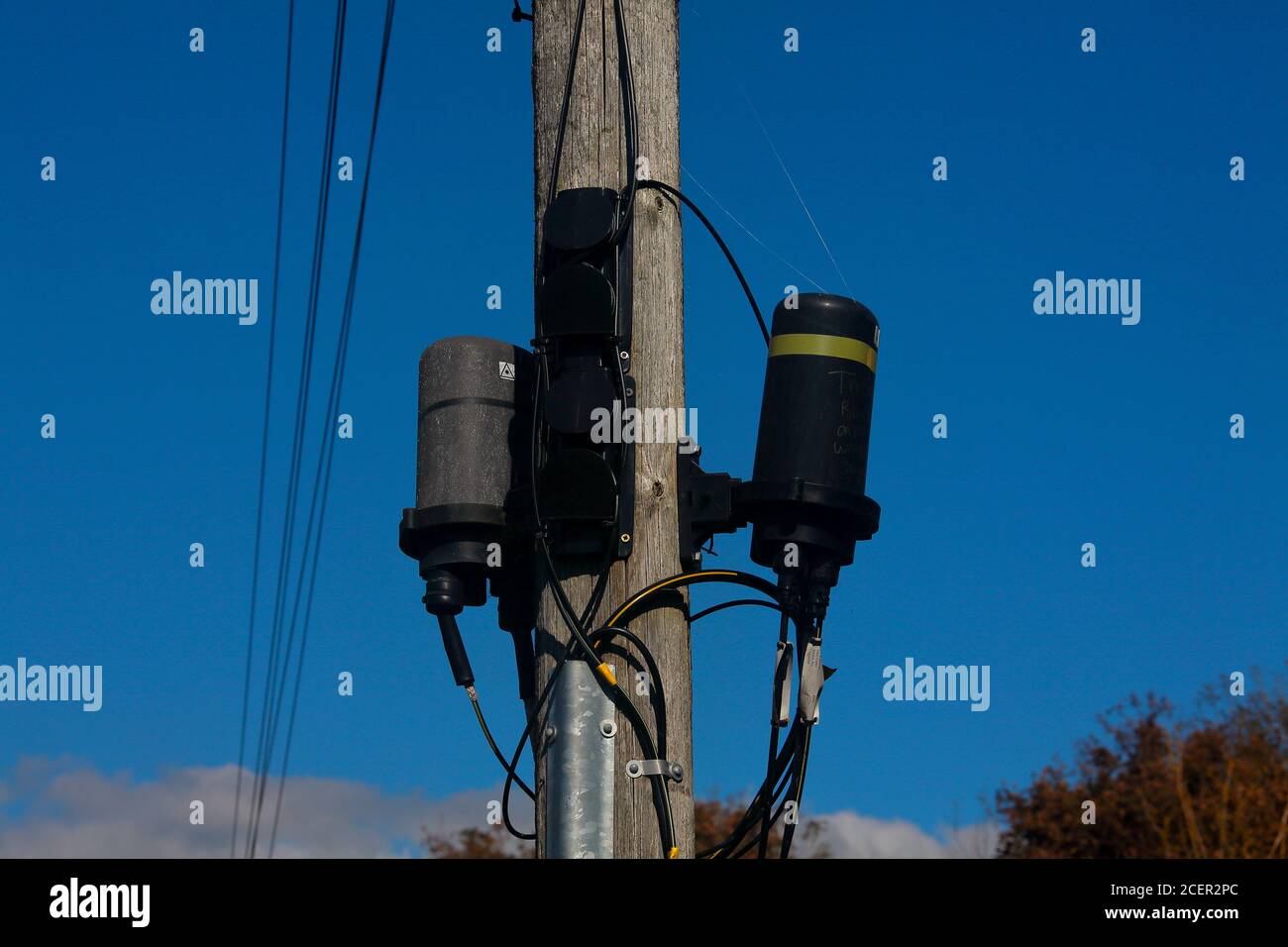 A pair of waterproof fibre optic cable joints mounted up a pole beside