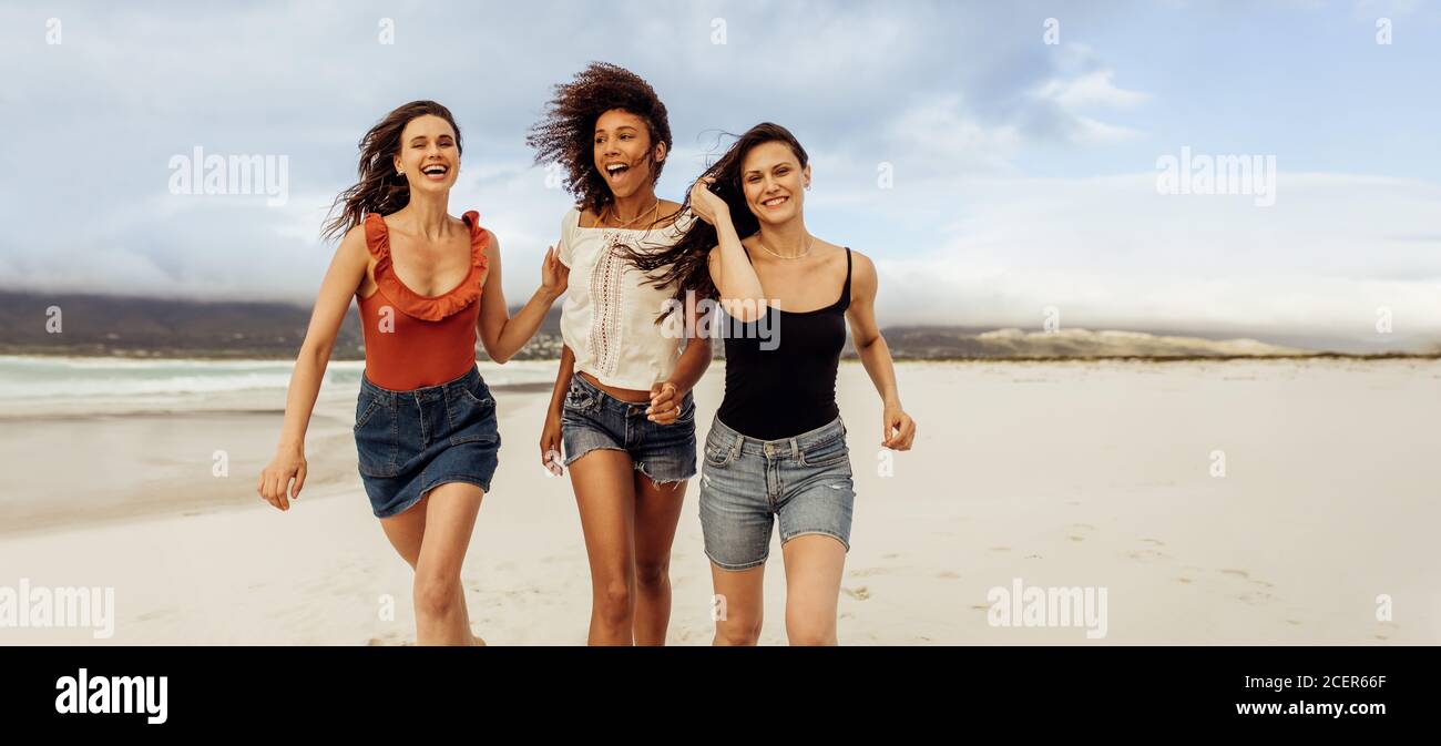 Happy friends having fun running on beach. Cheerful women friends on a beach holiday. Stock Photo