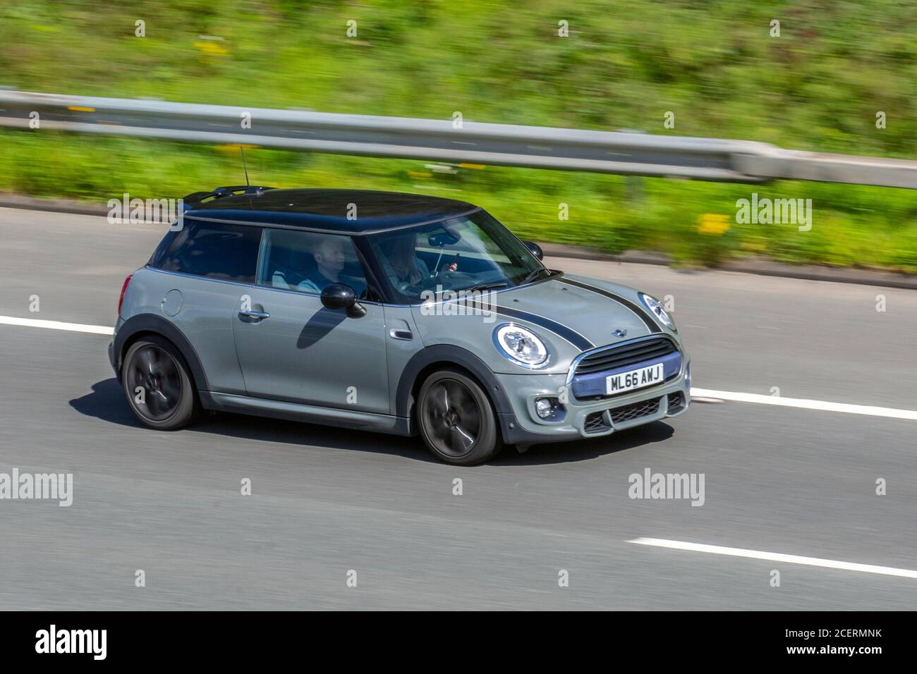 2016 grey Mini Cooper with black bonnet stripes; Vehicular traffic moving vehicles, cars driving vehicle on UK roads, motors, motoring on the M6 motorway highway network. Stock Photo