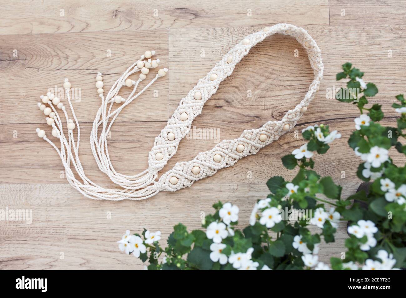 Handmade macrame dress belt. Natural cotton threads and wooden beads. Stylish decoration for women 's dress. Macrame braiding and cotton threads. Stock Photo