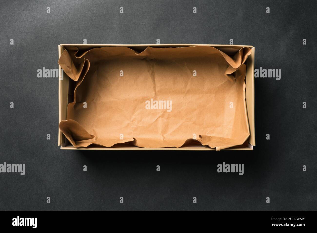 Open empty Shoe box, isolated on a black background. Crumpled brown paper. Packaging for men's and women's shoes or delivery of goods from the store Stock Photo