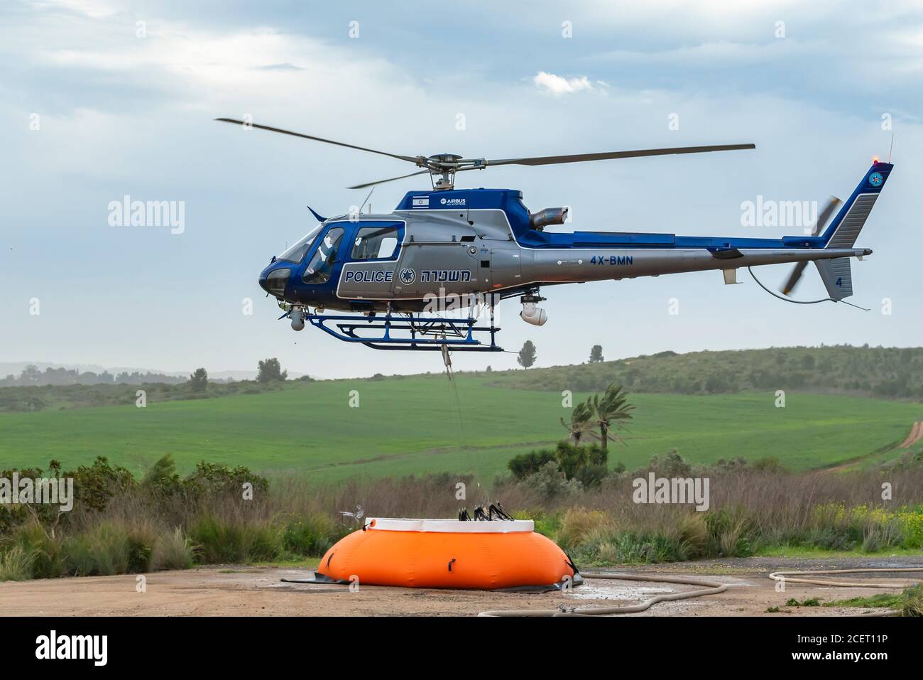 A police helicopter is used during a fire drill to airlift water to the fire zone. The water container is refilled from an inflatable pumpkin tank Stock Photo