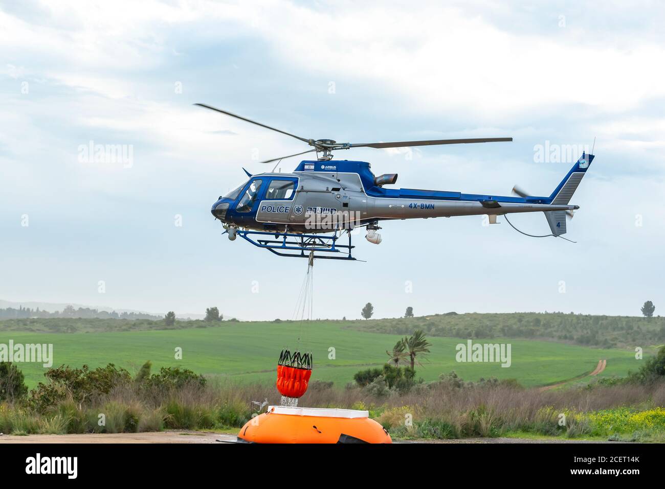 A police helicopter is used during a fire drill to airlift water to the fire zone. The water container is refilled from an inflatable pumpkin tank Stock Photo