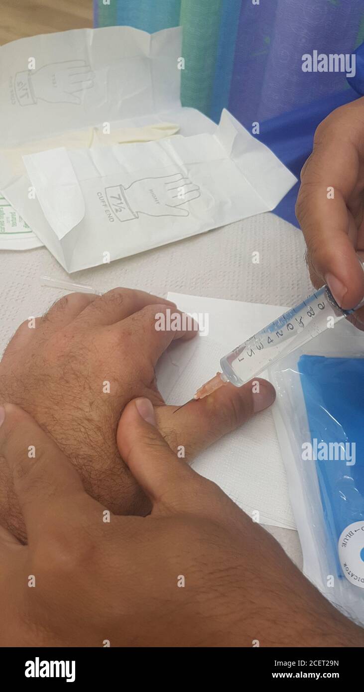 Anti tetanus is being injected to an injured thumb while using an electric rotary saw the worker injured his thumb on the revolving blade. luckily, th Stock Photo