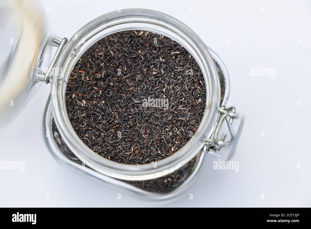 Assam loose leaf tea in a storage jar on a white canvas background ...
