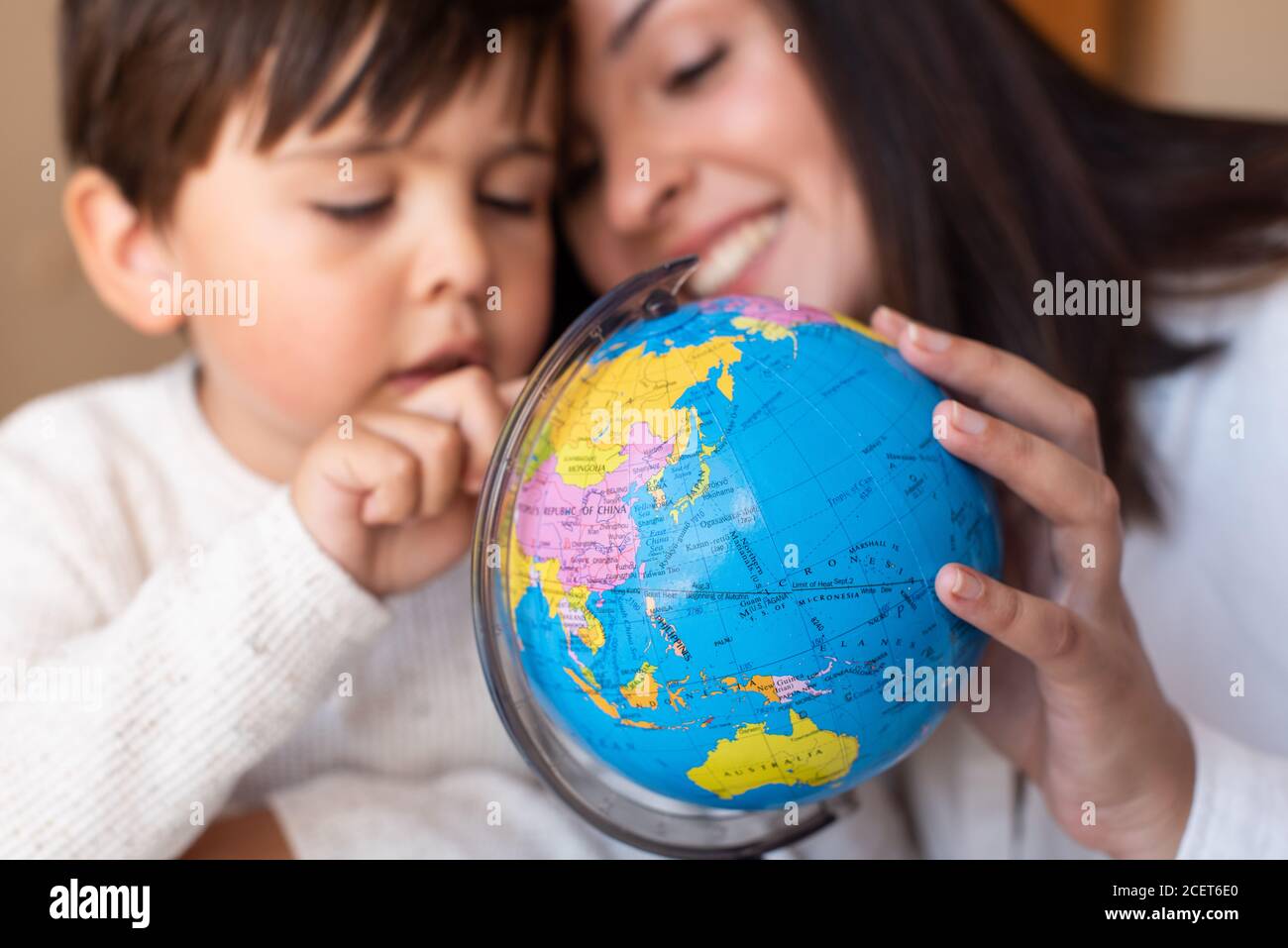 Liltle Preschooler Kid learing geography with a globe map and teacher educador help. Homeshooling. Learning Community. Montessori School Stock Photo