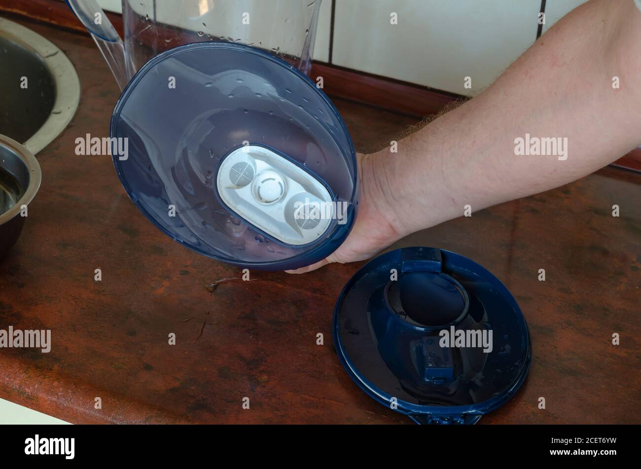 A male hand demonstrates a water jug with a new water purification ...