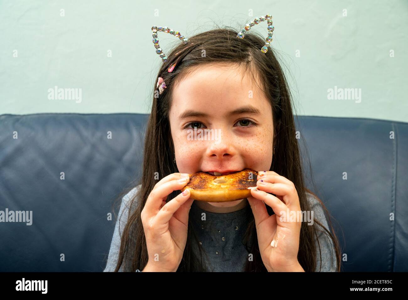 Young girl eating a toasted buttered bagel Stock Photo