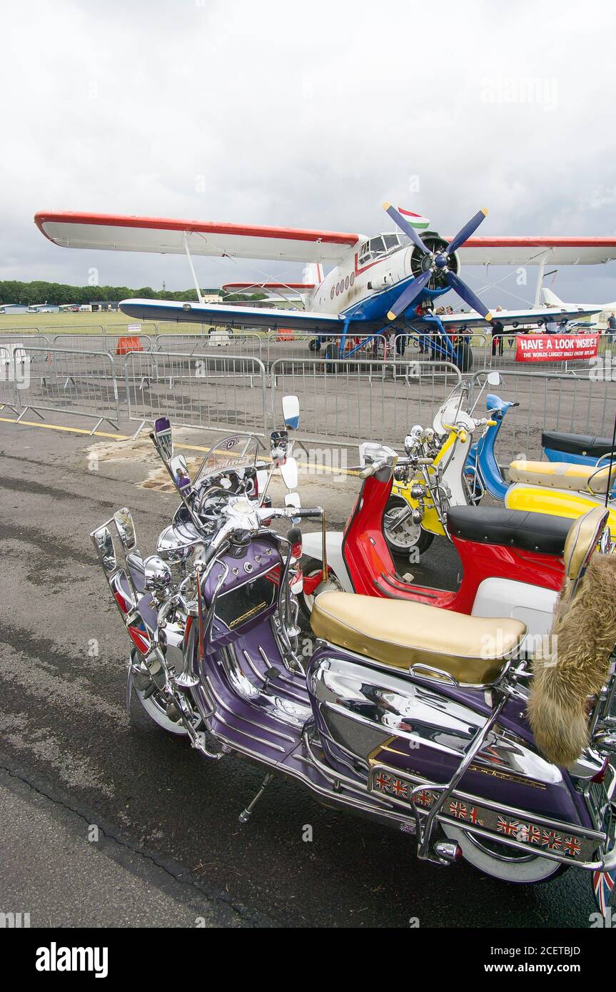 An old Lambretta motor scooter on display at a country fair at South Cerney Gloucestershire England UK with a Russian designed biplane AN-2 in the background Stock Photo