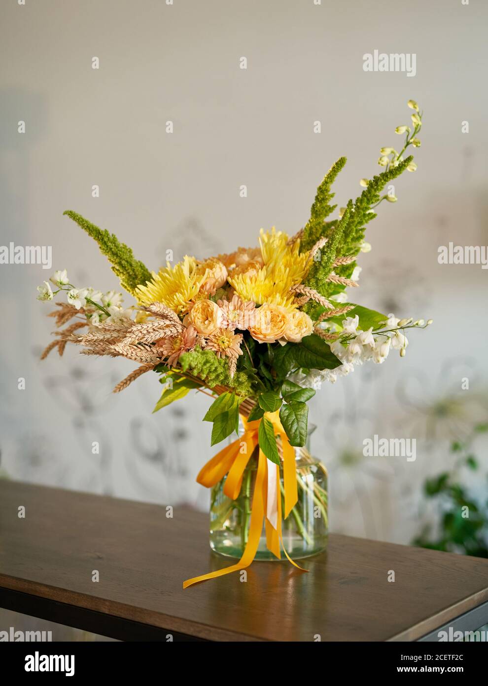 Beautiful blossoming flower bouquet of fresh chrysanthemums, roses, delphiniums, pigweeds and amaranths in yellow, beige and green colors in vase with Stock Photo