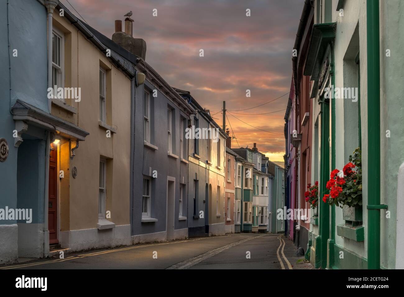 The first rays of sunshine start to light up the pastel colours of Irsha Street in the coastal village of Appledore in North Devon. Stock Photo