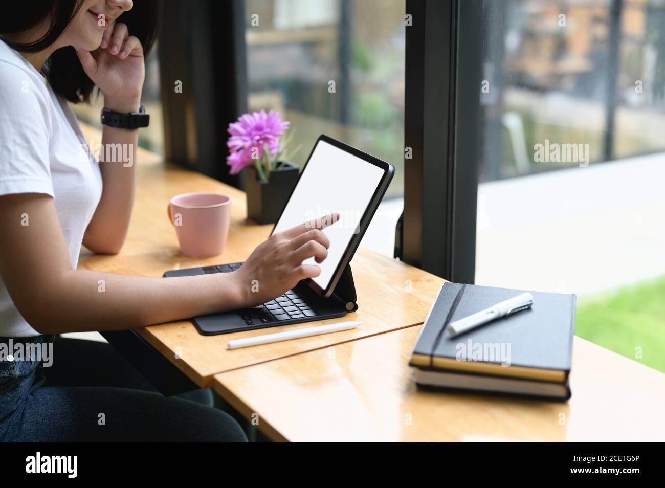 A beautiful woman is using a computer tablet with a white blank screen ...
