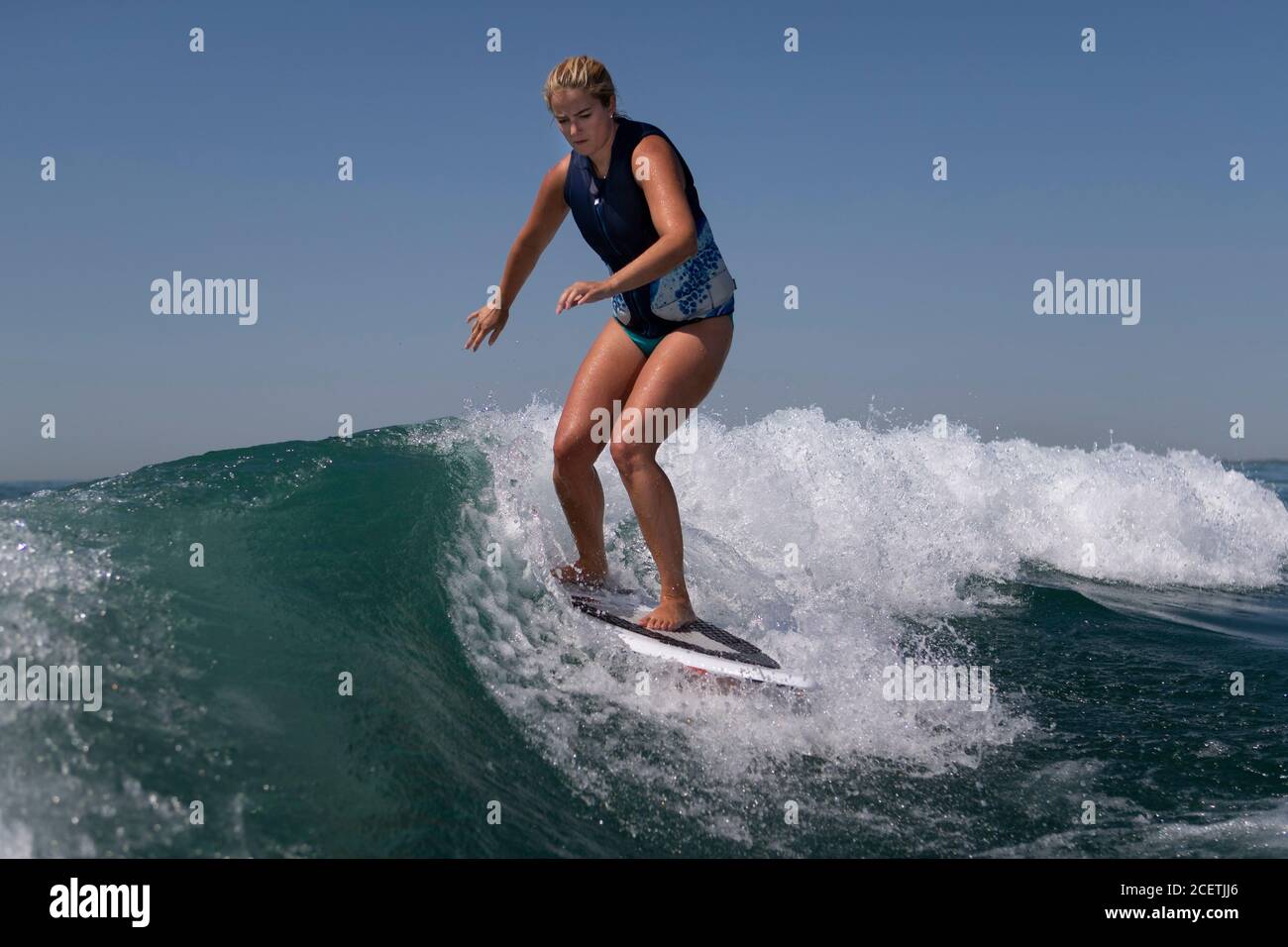 Woman riding a surfboard on a boat wake Stock Photo Alamy