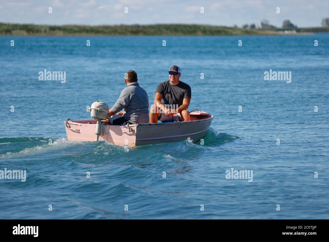 Two men in a small outboard-powered boat on a lake Stock Photo - Alamy