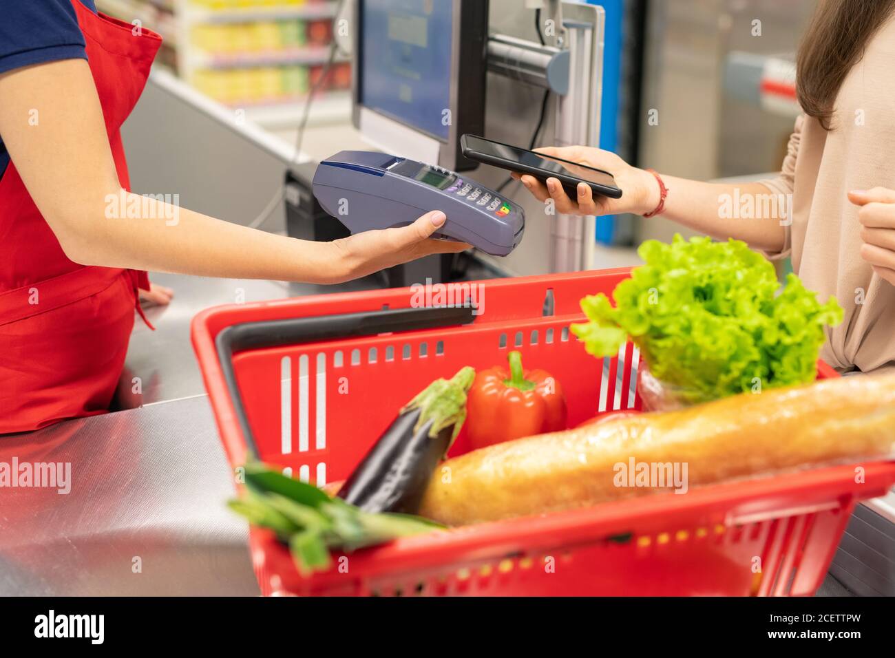 Unrecognizable young woman using NFC application on smartphone to pay for goods in modern store Stock Photo