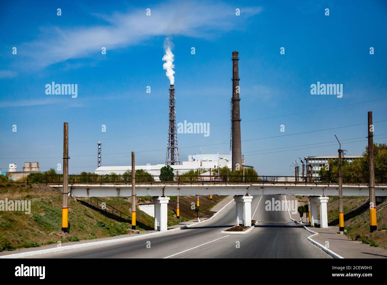 Smoking factory chimney or plant pipe of phosphoric fertilizers plant on blue sky. Old soviet chemical factory. Stock Photo