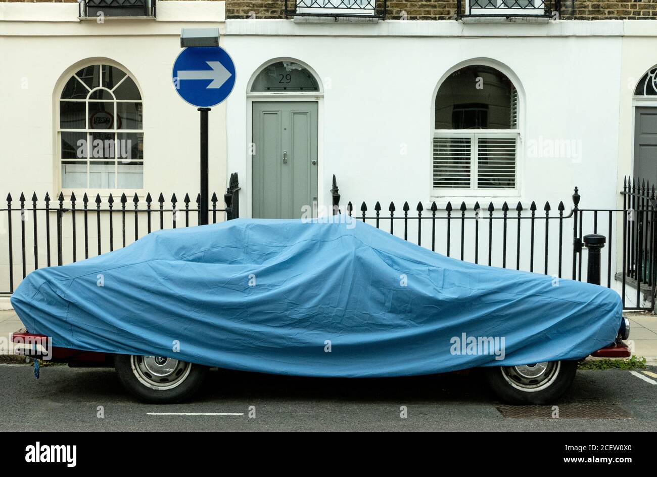 Car parked under a car cover on the street in Camden London UK Stock Photo