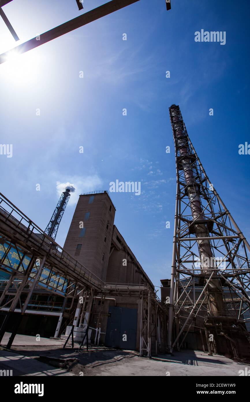 Smoking plant chimney and pipelines of chemical factory on blue sky. Phosphoric fertilizers plant. Stock Photo