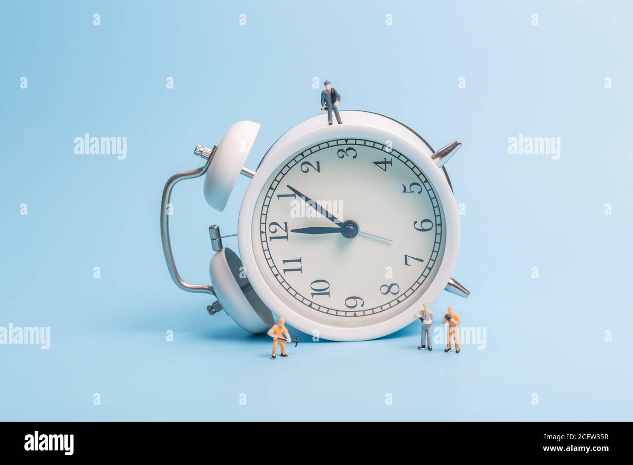 Alarm clock worker on blue background Stock Photo