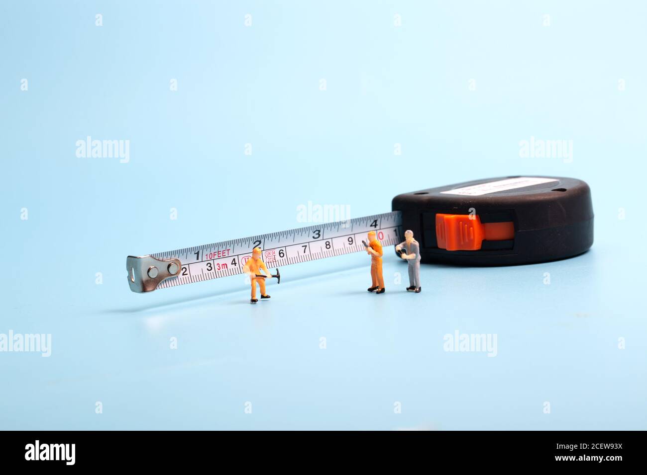 Meter stick and worker on blue background Stock Photo