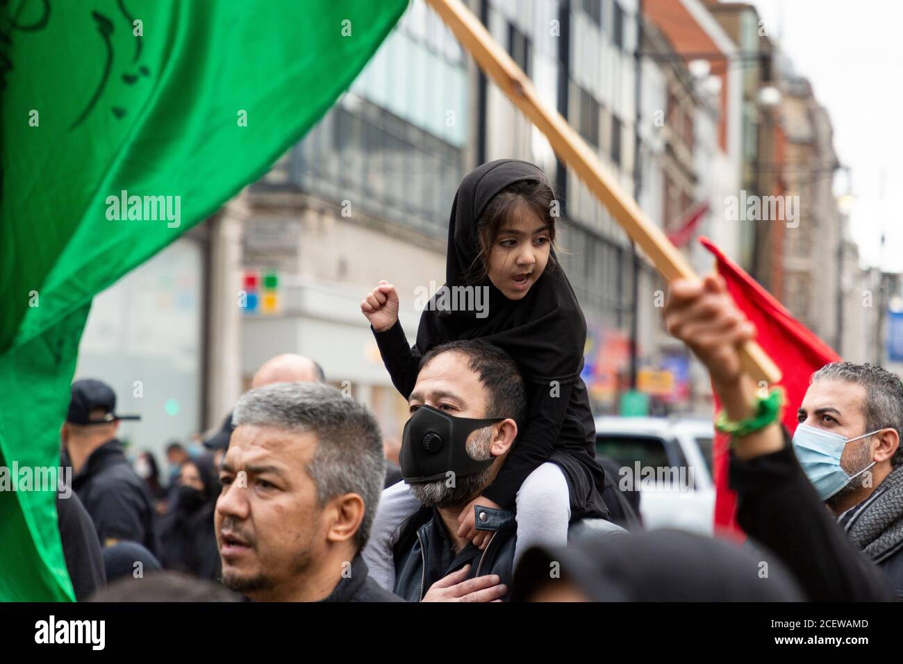 A young girl riding piggyback during Ashura Day event for Shia Muslims, Oxford Circus, London, 30 August 2020 Stock Photo