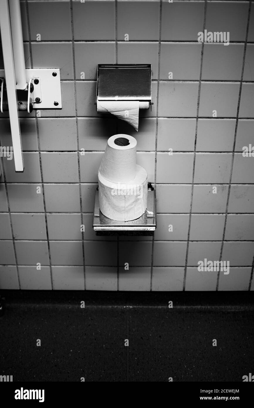 Creative image in black and white in grungy textured style of  toilet paper in a dirty bathroom. Stock Photo