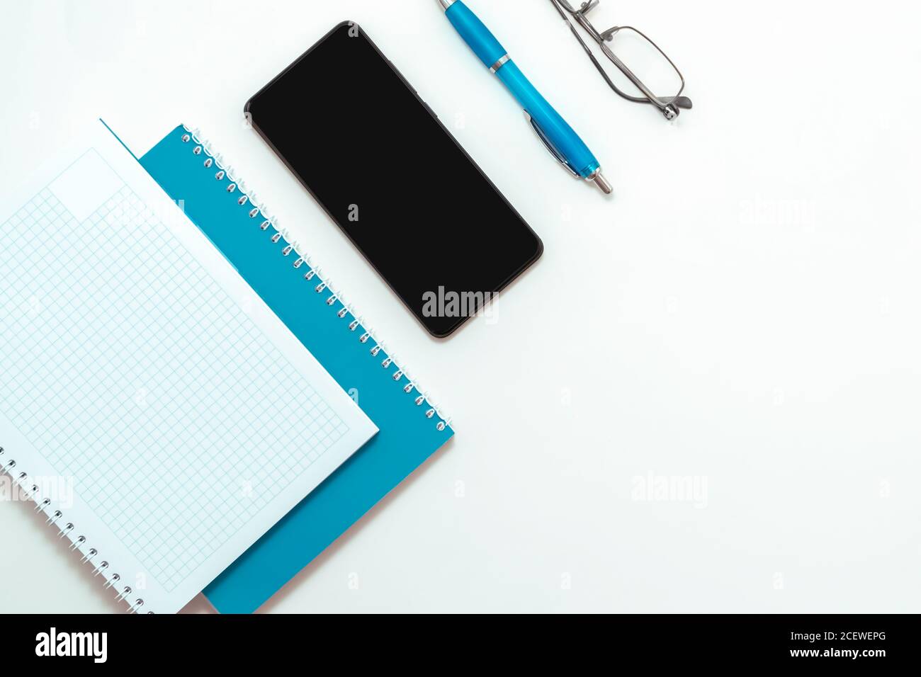 Stay at home white background flatlay. Home office smartphone blue notebook  glasses pen top view template long banner Stock Photo - Alamy