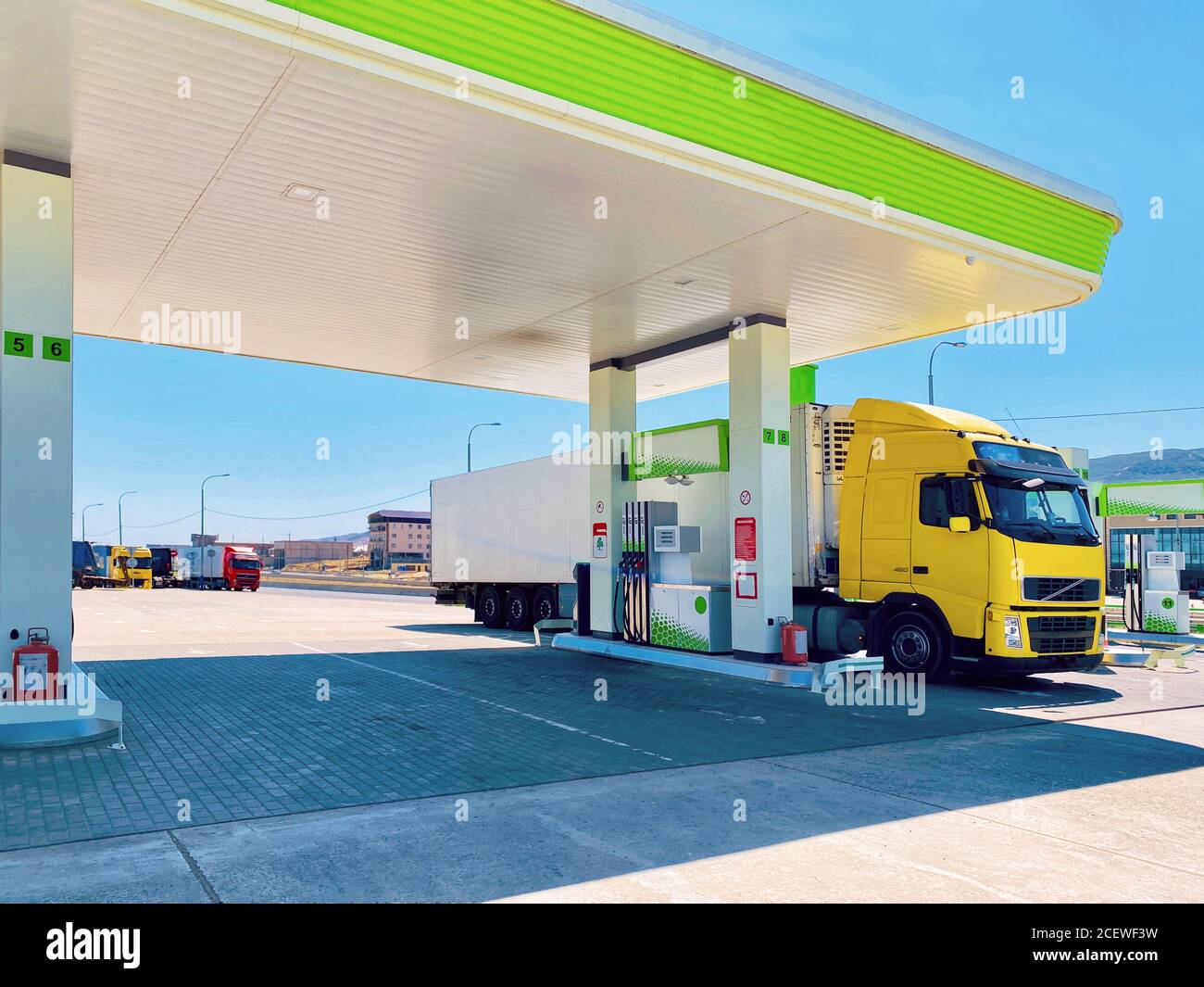 bright yellow truck with refrigerated semi-trailer at the fuel stop for refueling Stock Photo