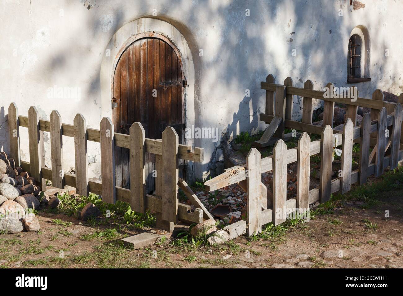 Locked wooden fenced monastery door, monastery yard in evening, rural scene in Europe Stock Photo