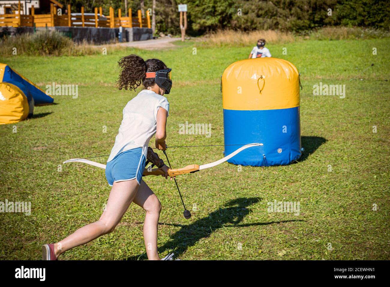 teenage girl running with bow and arrow during a game of archery tag ...