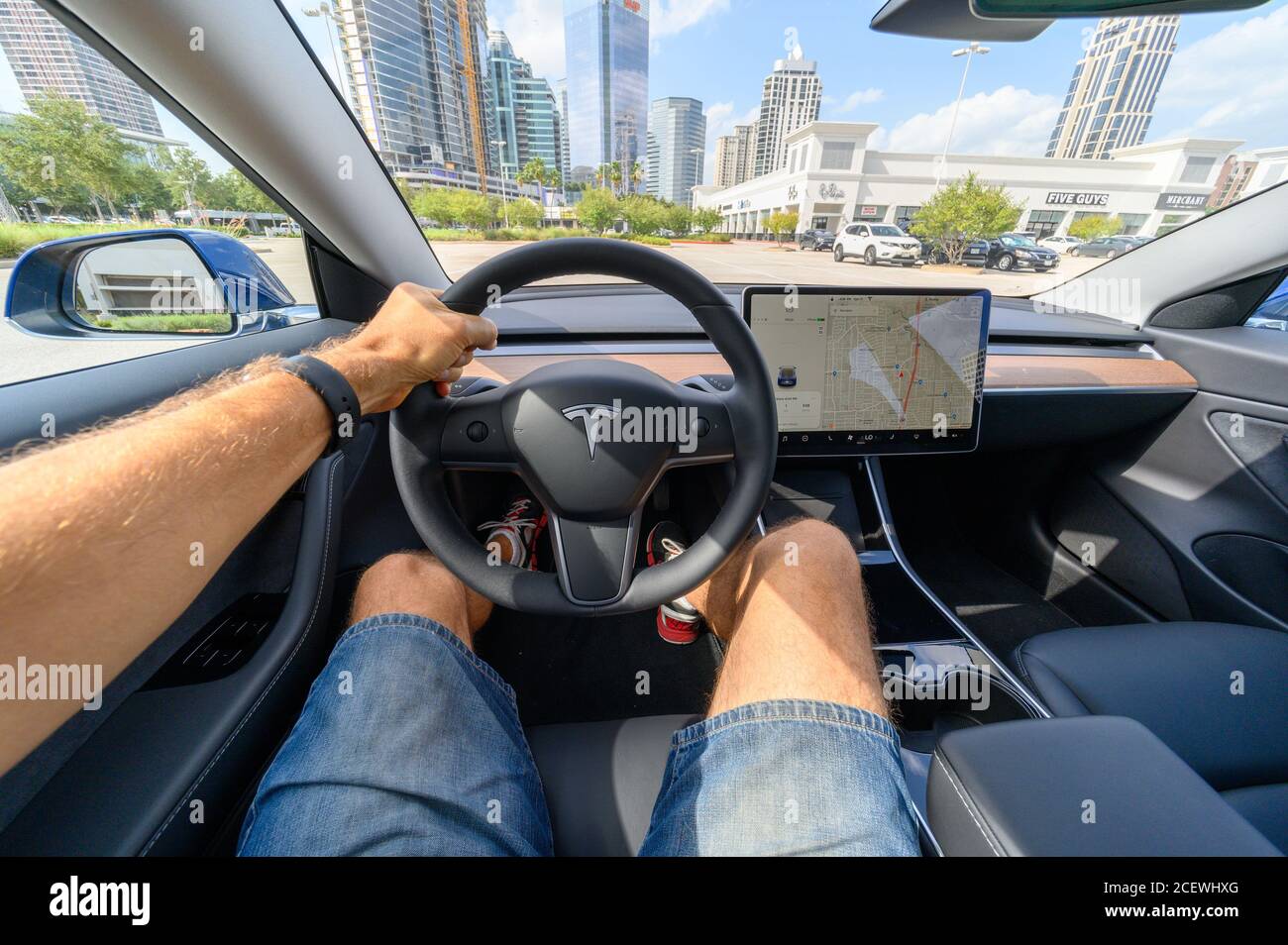Person driving a new Tesla car. The interior of a long-range, all-electric, sedan Tesla Model 3 AWD with a range of 320 miles Stock Photo