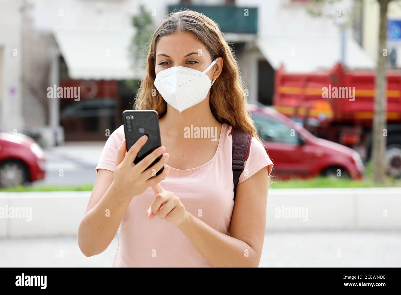 Latin American woman with smart phone wearing face protective mask in the street Stock Photo