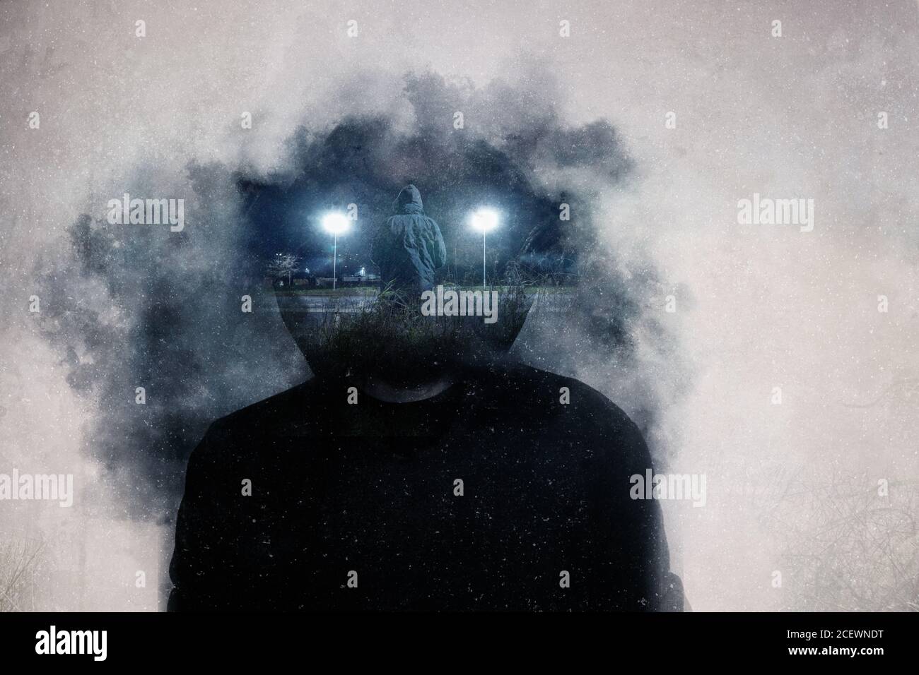 A mental health concept. A mans head covered in clouds. With a double exposure of a mans standing next to two glowing street lights Stock Photo