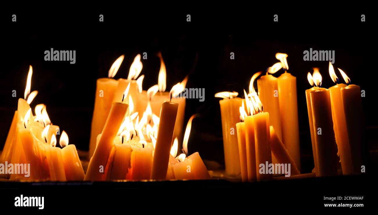 Religious candle light on black background. Yellow candlelight flame in