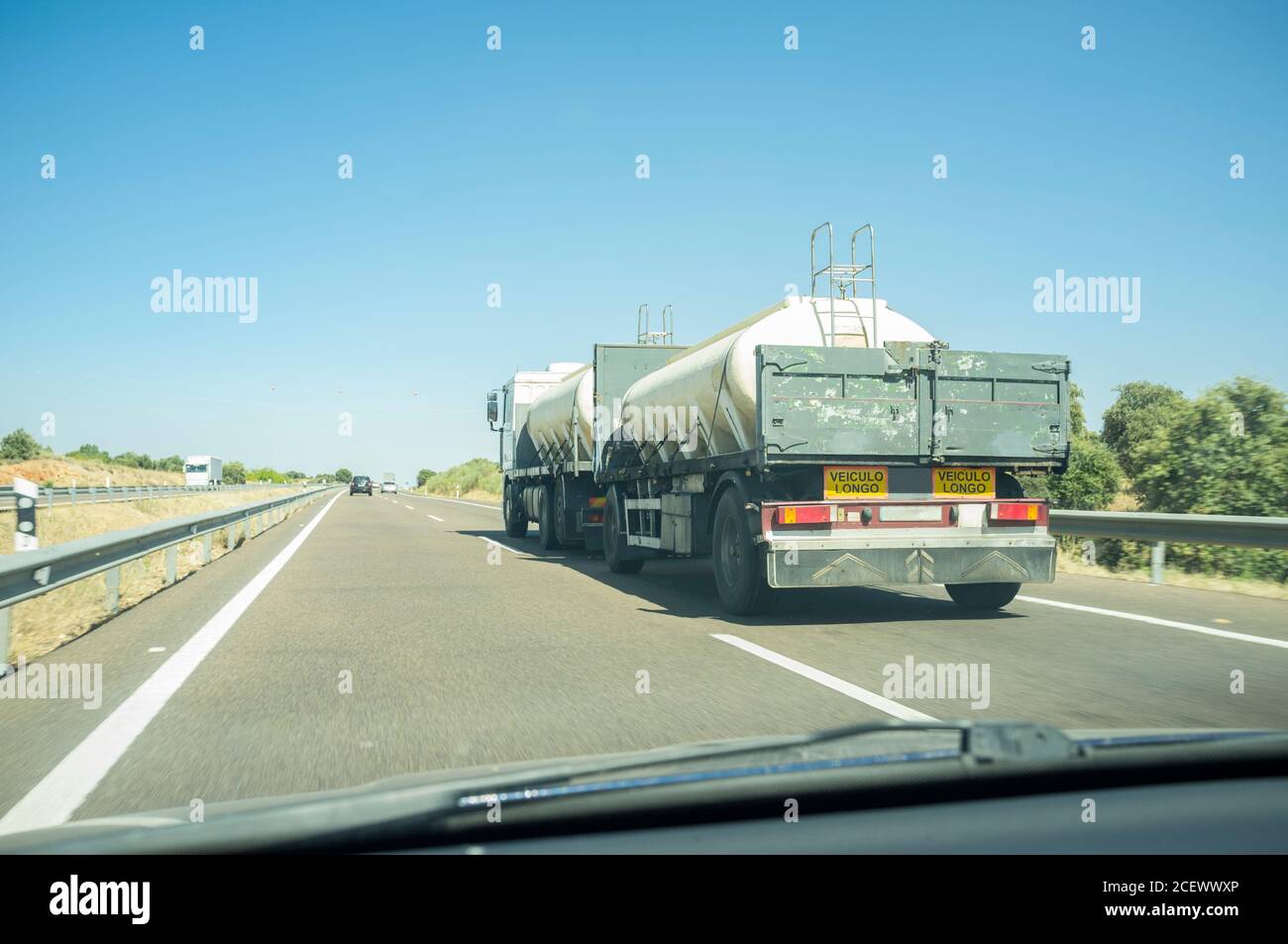 Driving behind B-double trailer loading tanks on divided highway road. View from the inside of the car Stock Photo