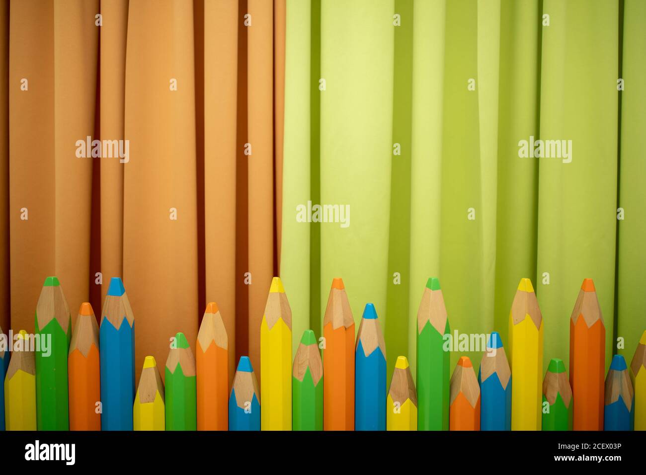 Colorful pencils on green and orange background Stock Photo