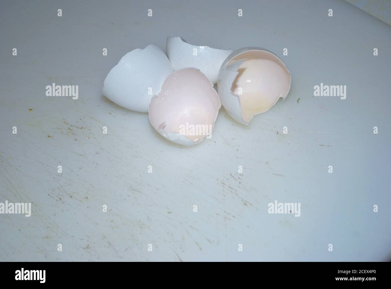 Close up of two cracked eggshells on a well used cutting board Stock Photo