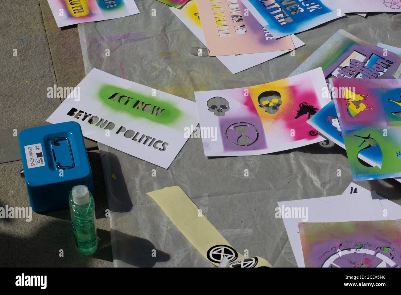 Protesters spraying erasable chalk paint onto bee and Extinction Rebellion symbol stencil design Stock Photo