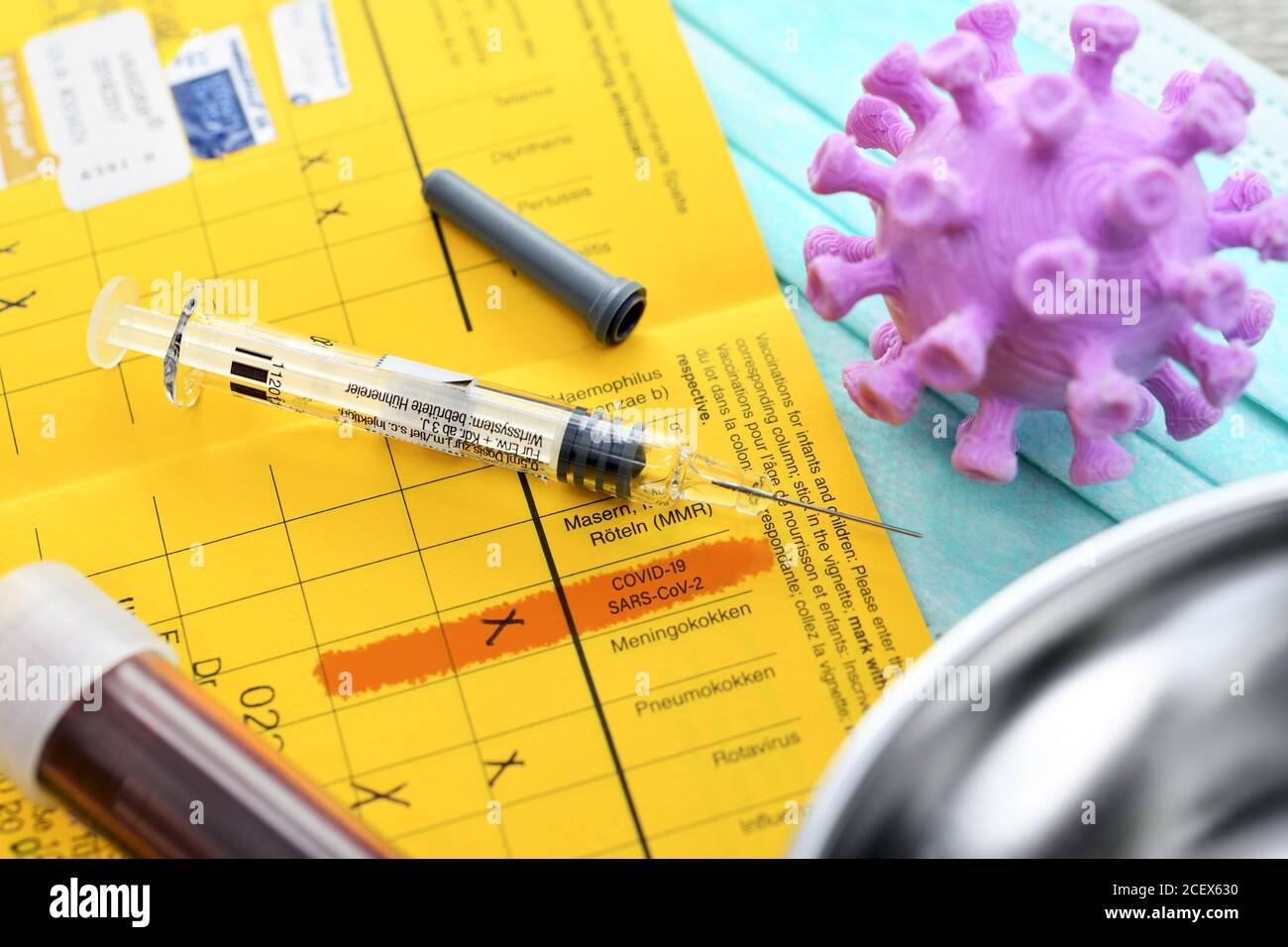 Syringe, blood collection tube, coronavirus model and vaccination card, corona vaccination Stock Photo