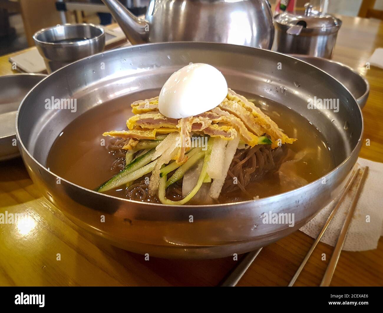 Jinju Naengmyeon, noodle dish of handmade noodles made from buckwheat and cold broth made from beef. Topped with Yukjeon, Korean style beef pancake. Stock Photo