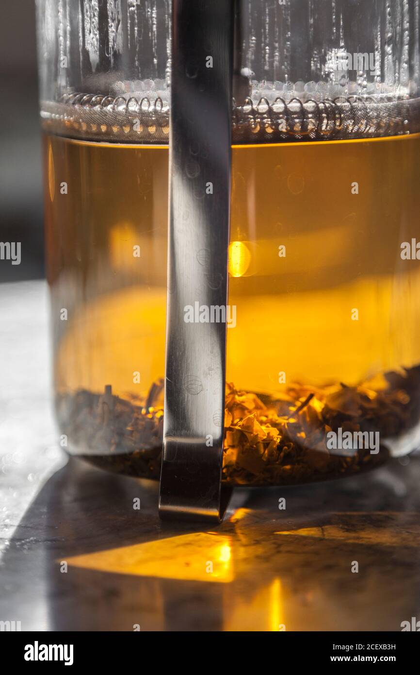 Loose leaf tea steeps in a french press on a white marble countertop