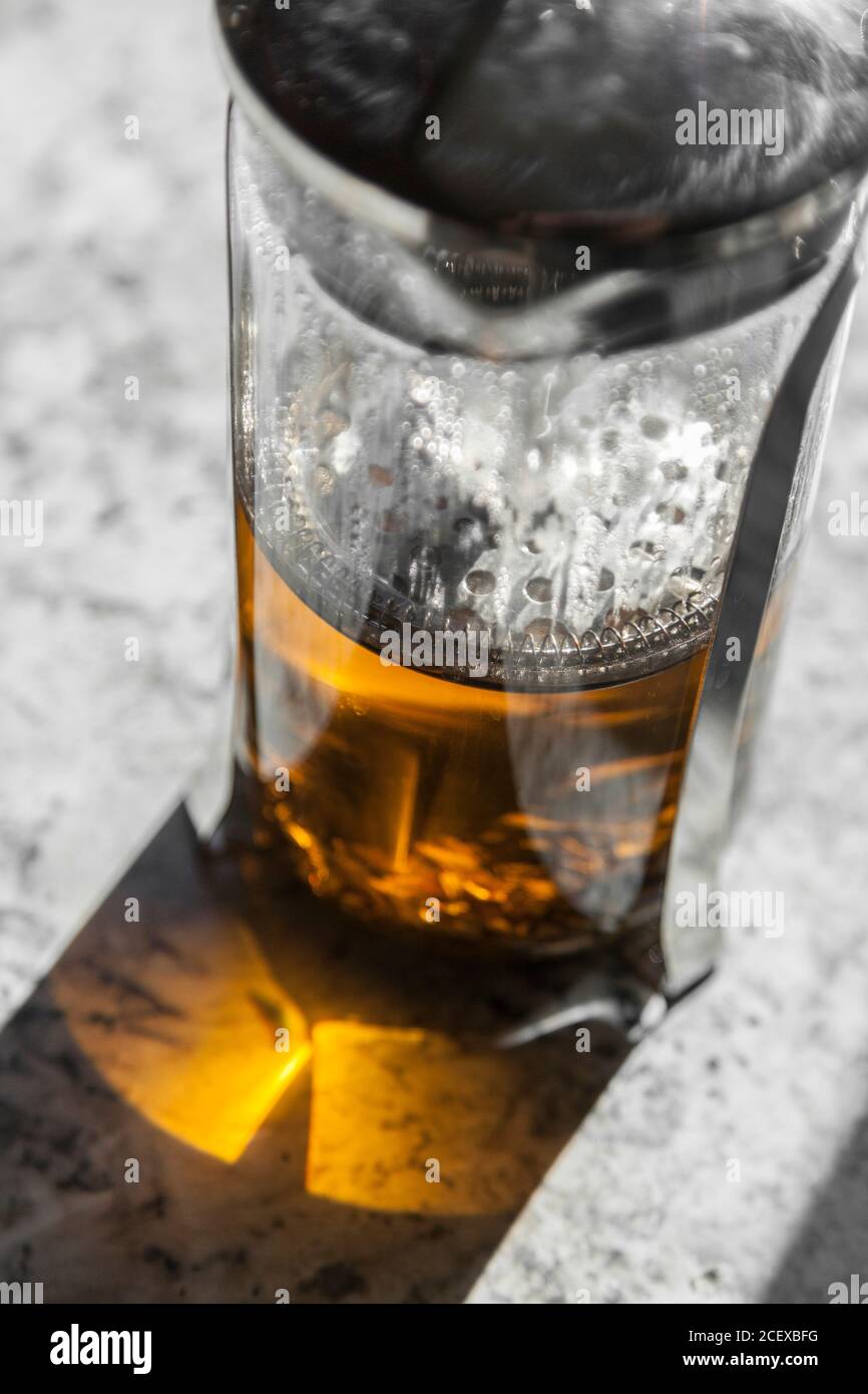 Loose leaf tea steeps in a french press on a white marble countertop