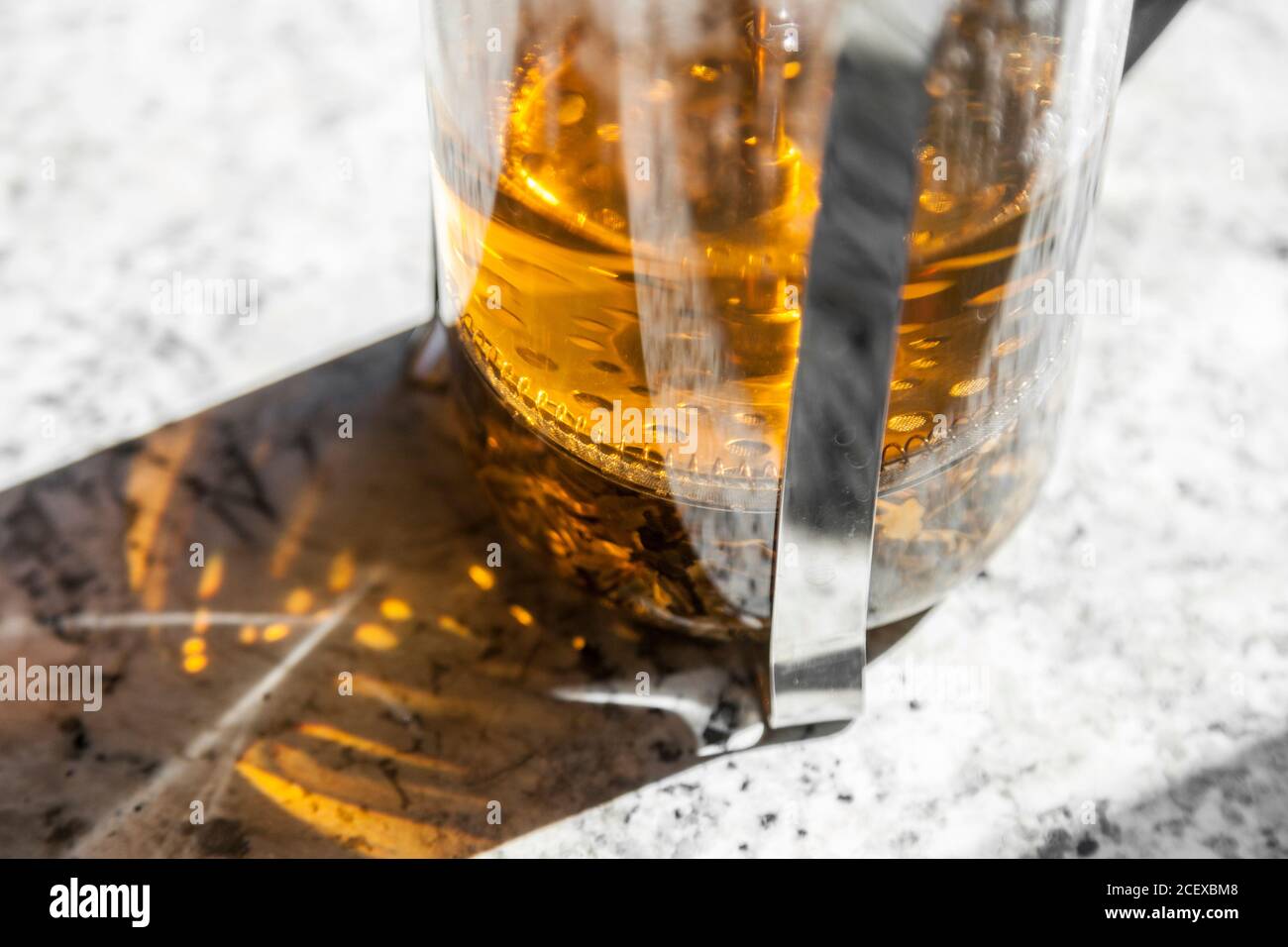 Loose leaf tea steeps in a french press on a white marble countertop