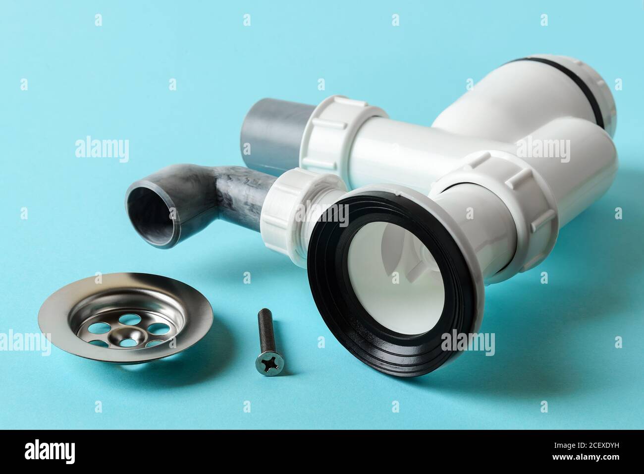 Metal strainer near assembled sink bottle trap on a blue background